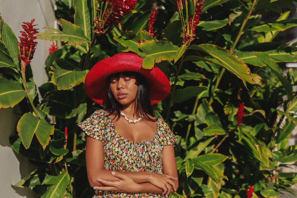 Model wearing Monica 5" Wide Brim Red Packable Straw Sun Hat handmade loomed raffia in a solid hue of red lightweight malleable flexible sun protection hat - Shebobo