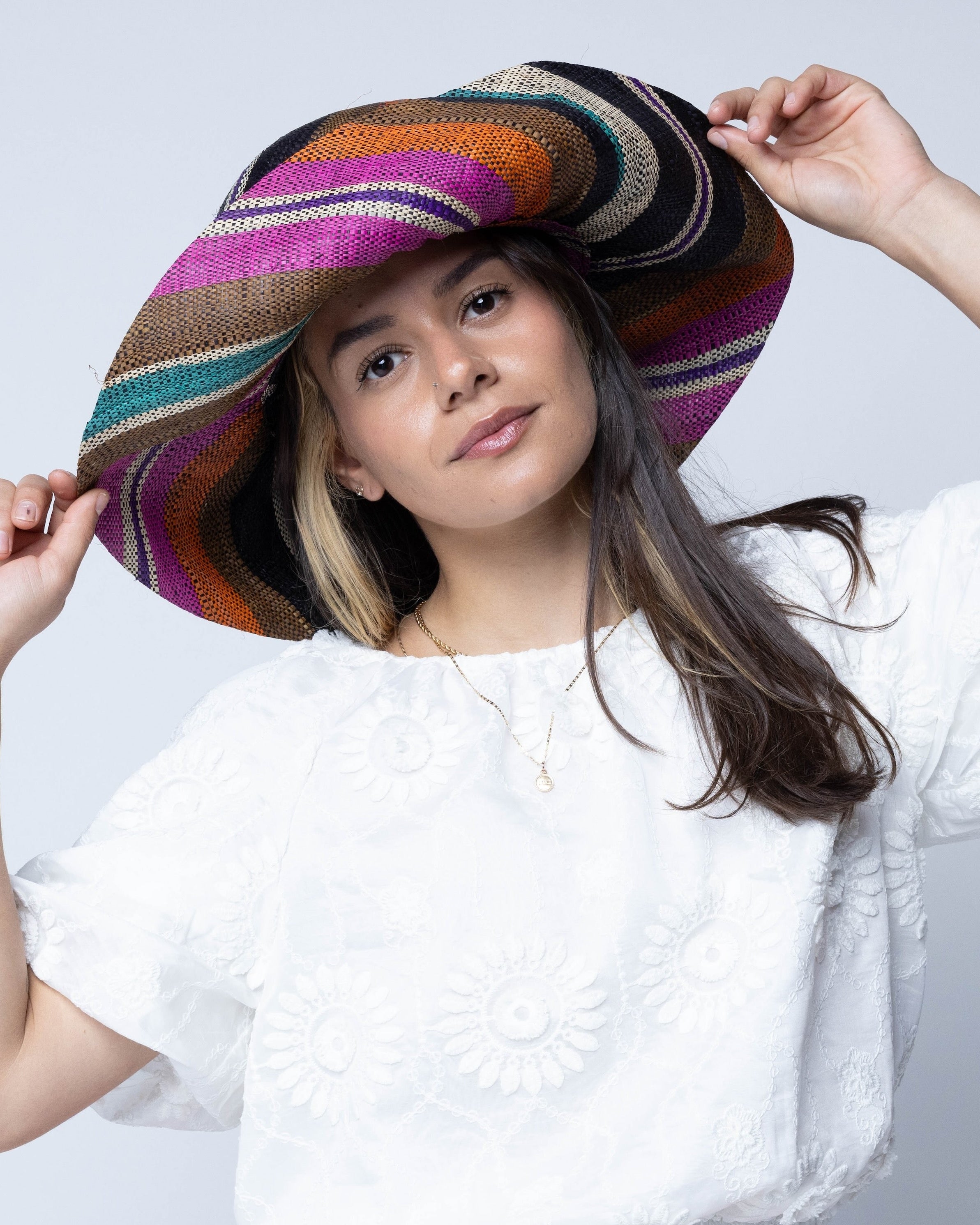 Model wearing Monica 5" Wide Brim Revel Swirl Multicolor Stripes Packable Straw Sun Hat Handmade loomed raffia in multi width bands of coral orange, fuchsia pink, teal blue/green, purple, cinnamon/tobacco/brown, black, natural straw color etc. create a swirl pattern - Shebobo