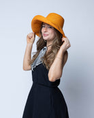 Model wearing Monica 5" Wide Brim Saffron Packable Straw Sun Hat handmade loomed raffia in a solid hue of saffron yellow/orange lightweight malleable flexible hat - Shebobo