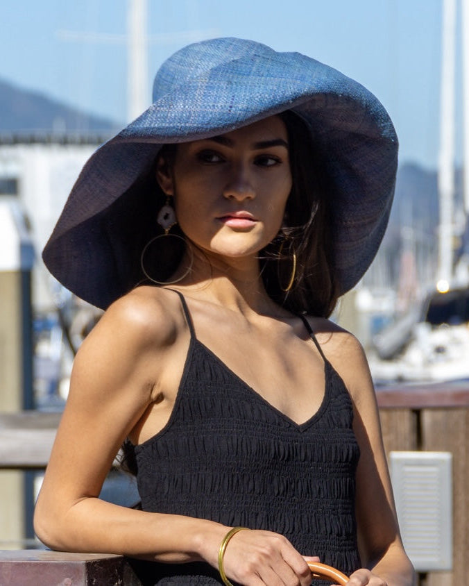 Model wearing Monica 7" Wide Brim Turquoise Packable Straw Sun Hat handmade loomed raffia in a solid hue of turquoise blue lightweight malleable flexible sun protection hat - Shebobo