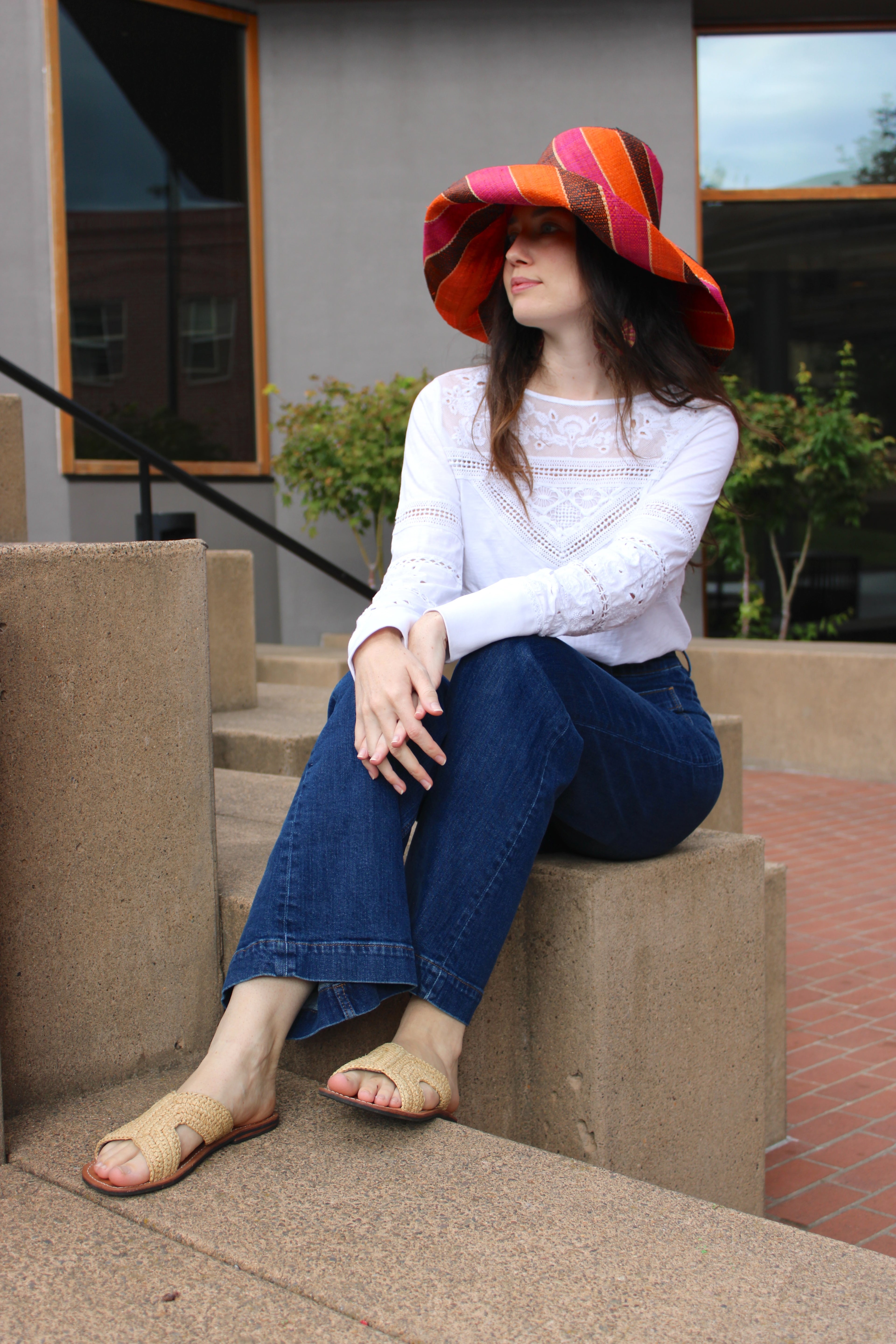 Model wearing Monica 7" Wide Brim Whimsy Swirl Multicolor Stripes Packable Straw Sun Hat Handmade loomed raffia in multi width bands of coral orange, fuchsia pink, black, natural straw color, etc. create a swirl pattern - Shebobo (with Lizzie Crochet Straw & Leather Sandal Shoes)
