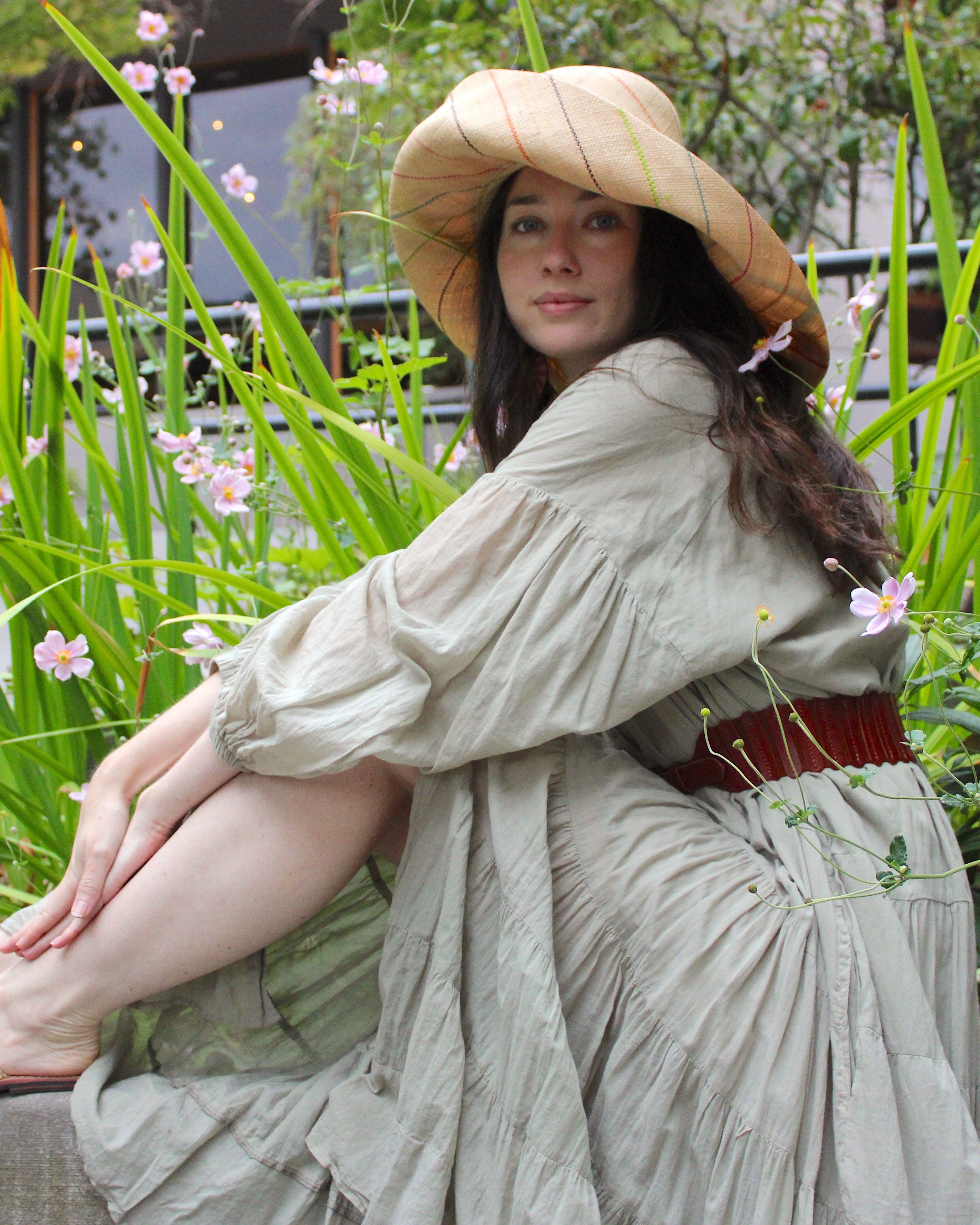 Model wearing Monica 5" or 7" wide brim natural and brights multicolor pinstripes packable raffia straw hat handmade loomed raffia in wide bands of natural straw color with narrow bands of lime green, bordeaux red, fuchsia pink, orange, cinnaon/tobacco/brown, blush orange/pink, etc. create a stripe swirl pattern - Shebobo