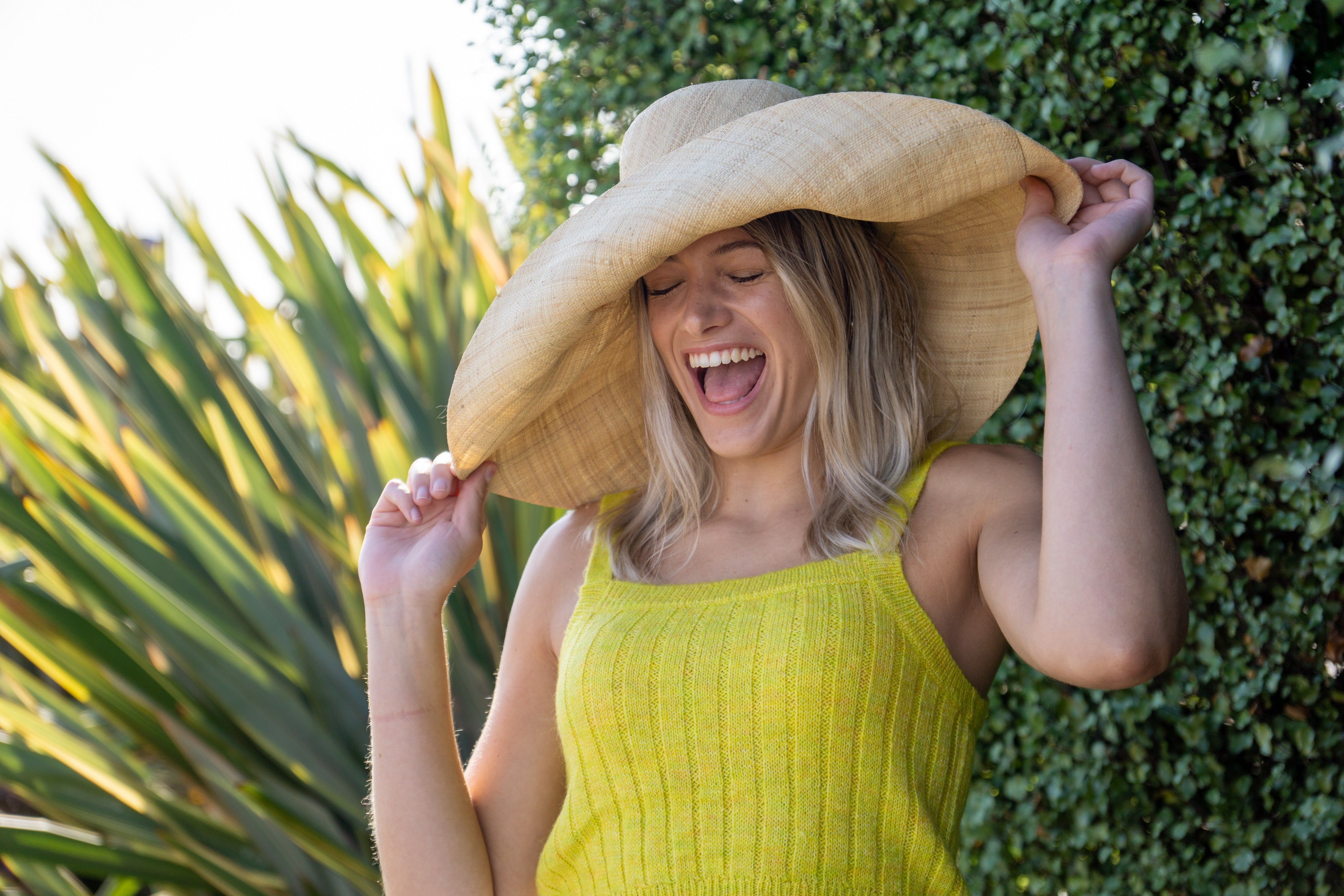 Model wearing Monica 7" Wide Brim Solid Color Packable Straw Sun Hats handmade loomed natural raffia palm fiber in a solid hue of natural straw color lightweight, packable, breathable, uv protection hat - Shebobo