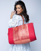 Model wearing Large Monte Carlo Wynwood Big Straw Beach Bag with Metallic Detailing Red Shoulder Bag handmade loomed raffia palm fiber in a solid hue of Red with incorporated woven in vegan leather gold metallic strands and leather handles purse - Shebobo