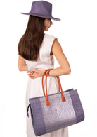 Model wearing Monte Carlo Wynwood Big Straw Beach Bag with Metallic Detailing Denim Shoulder Bag handmade loomed raffia palm fiber in a solid hue of denim retro/light blue with incorporated woven in vegan leather silver metallic strands and leather handles purse - Shebobo (with Panama Unisex Straw Hats Denim)