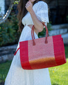 Model wearing Monte Carlo Wynwood Big Straw Beach Bag with Metallic Detailing Red Shoulder Bag handmade loomed raffia palm fiber in a solid hue of Red with incorporated woven in vegan leather gold metallic strands and leather handles purse - Shebobo