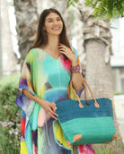 Model wearing Model wearing Monterey Two Tone Straw Tote Bag handmade loomed raffia fibers in a color block pattern of turquoise blue colored upper half, and seafoam blue/green lower half - Shebobo