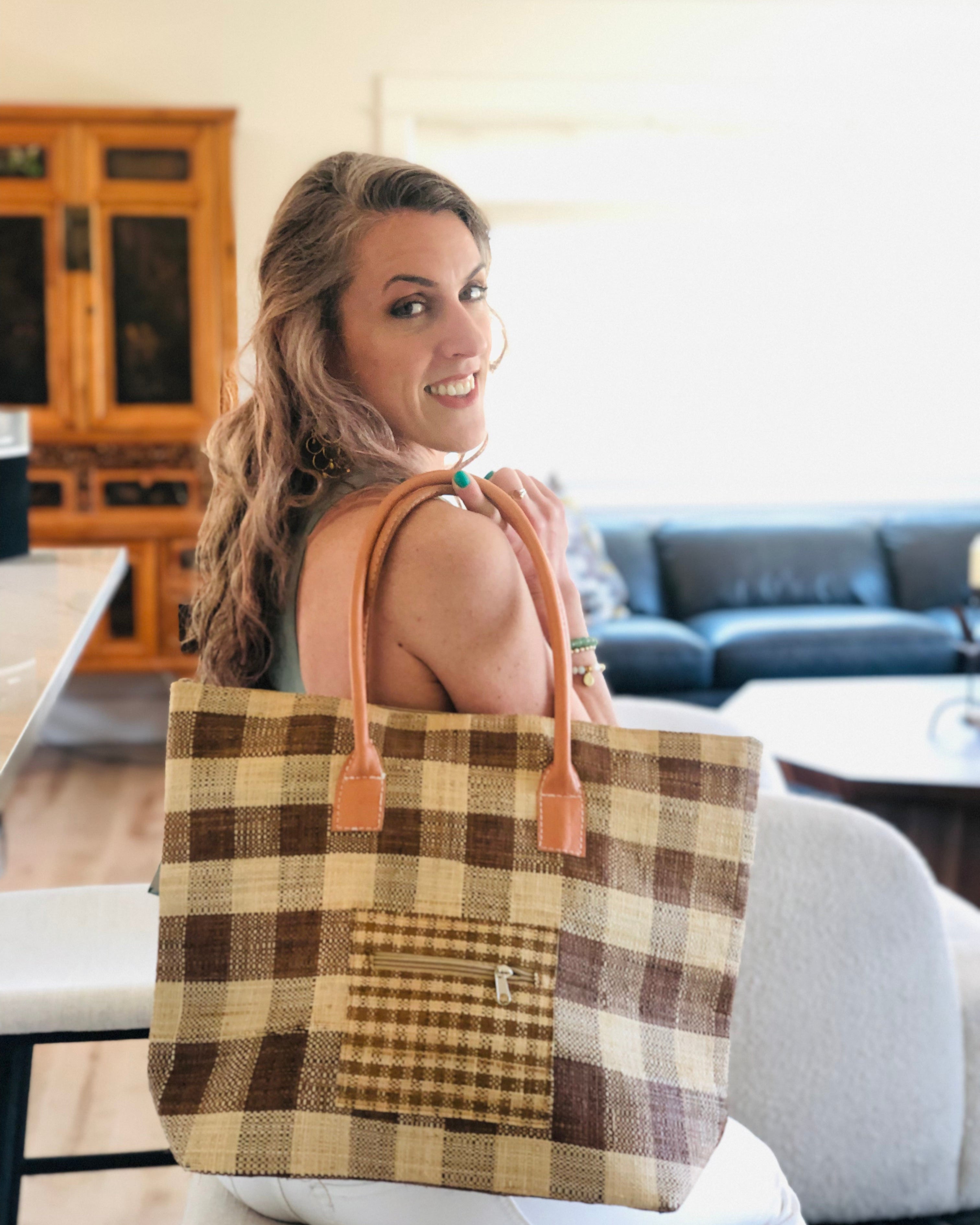 Model wearing Nador Gingham Zippered Straw Bag in two tone cinnamon/tobacco/brown and natural straw color plaid pattern handbag handmade from loomed raffia palm shopping tote that packs flat with zipper closure and leather handles beach bag purse - Shebobo