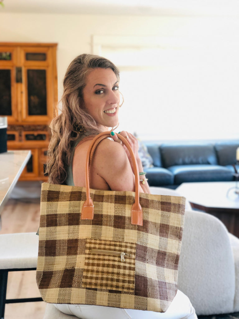 Model wearing Nador Gingham Zippered Straw Bag in two tone cinnamon/tobacco/brown and natural straw color plaid pattern handbag handmade from loomed raffia palm shopping tote that packs flat with zipper closure and leather handles beach bag purse - Shebobo