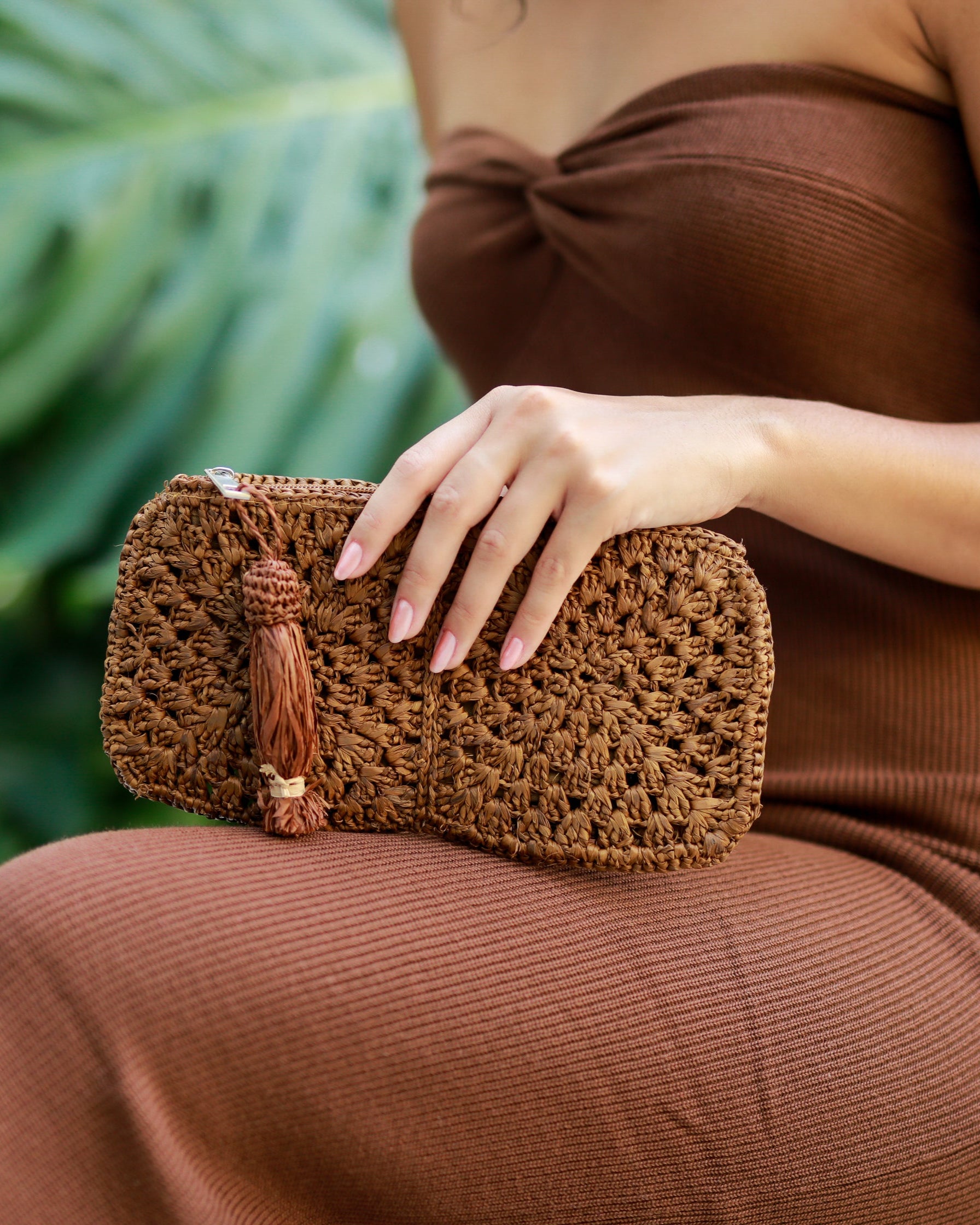 Model wearing Nasolo Crochet Straw Clutch bag with zipper closure and tassel zipper pull handmade granny square pattern raffia pouch purse in cinnamon/tobacco/brown handbag - Shebobo