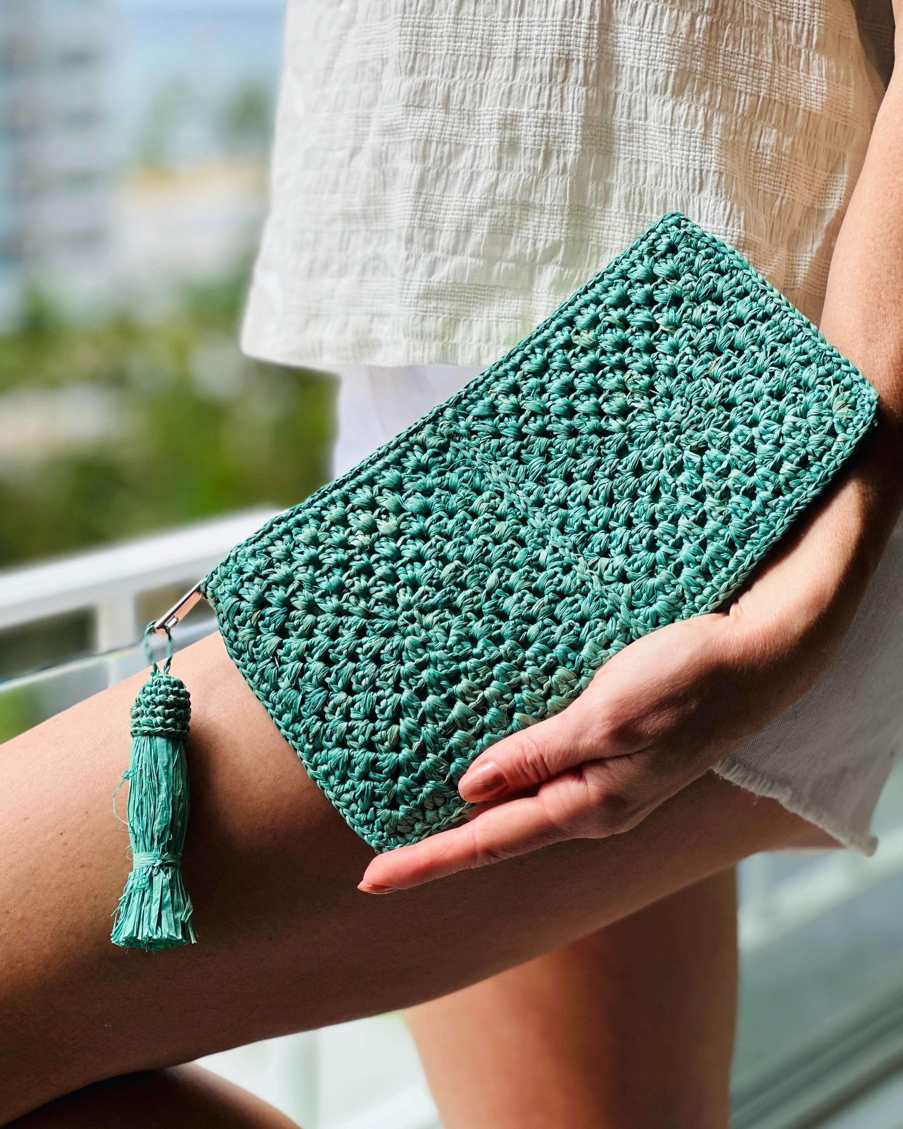 Model wearing Nasolo Crochet Straw Clutch bag with zipper closure and tassel zipper pull handmade granny square pattern raffia pouch purse in seafoam blue/green handbag - Shebobo