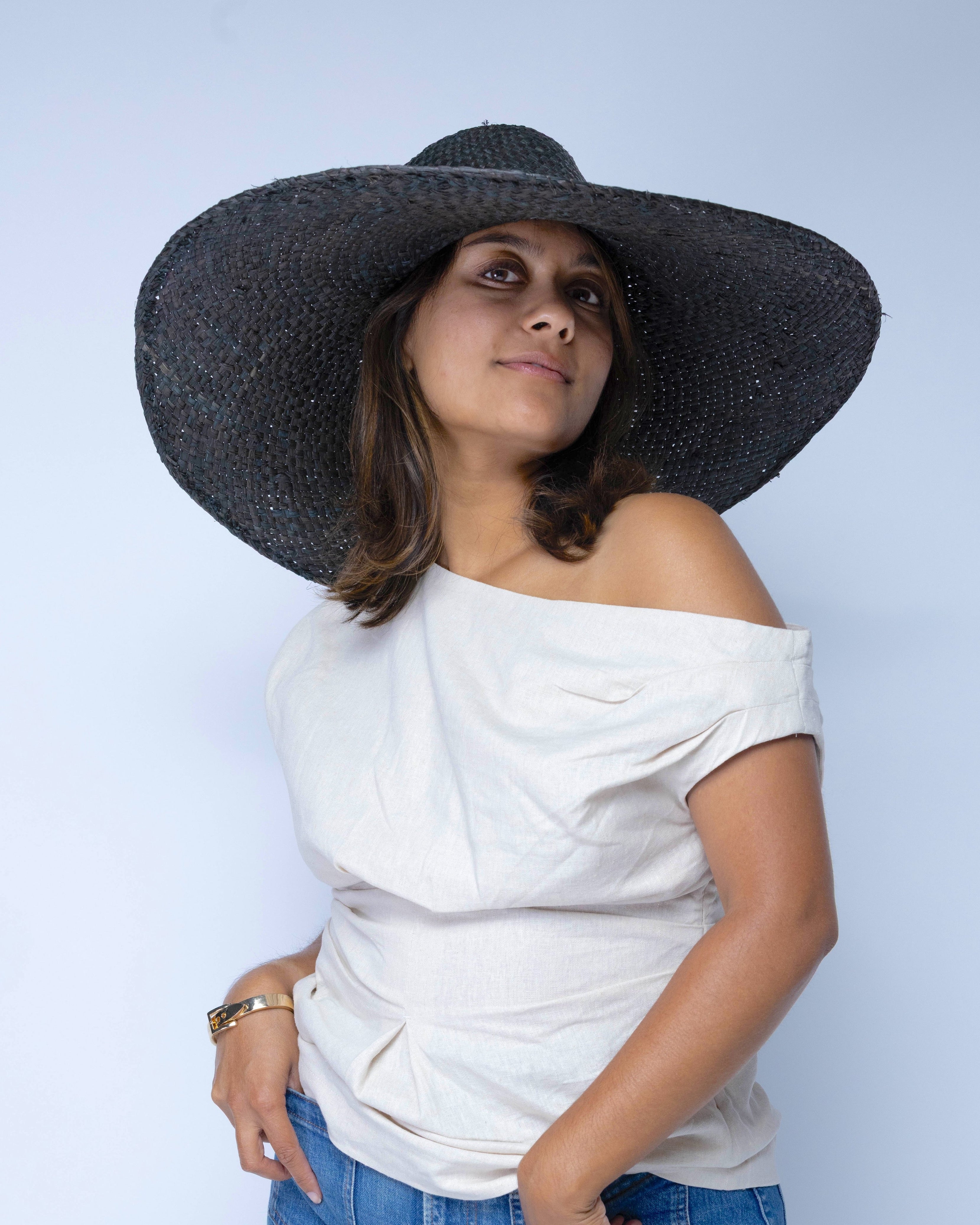Model wearing 7" Wide Brim Natasha Black Woven XL Straw Sun Hat handmade woven natural raffia palm fiber in a solid hue of black with matching adjustable twisted raffia hat band and and extra wide brim - Shebobo