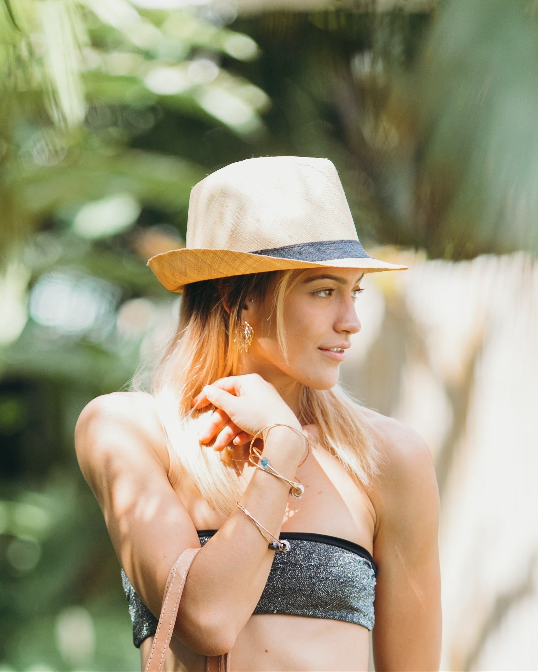 Model wearing Fedra Natural with Black Hat Band - Unisex Fedora Straw Hat handmade loomed natural raffia palm fiber in a solid hue of natural straw color with an attached black hat band - Shebobo