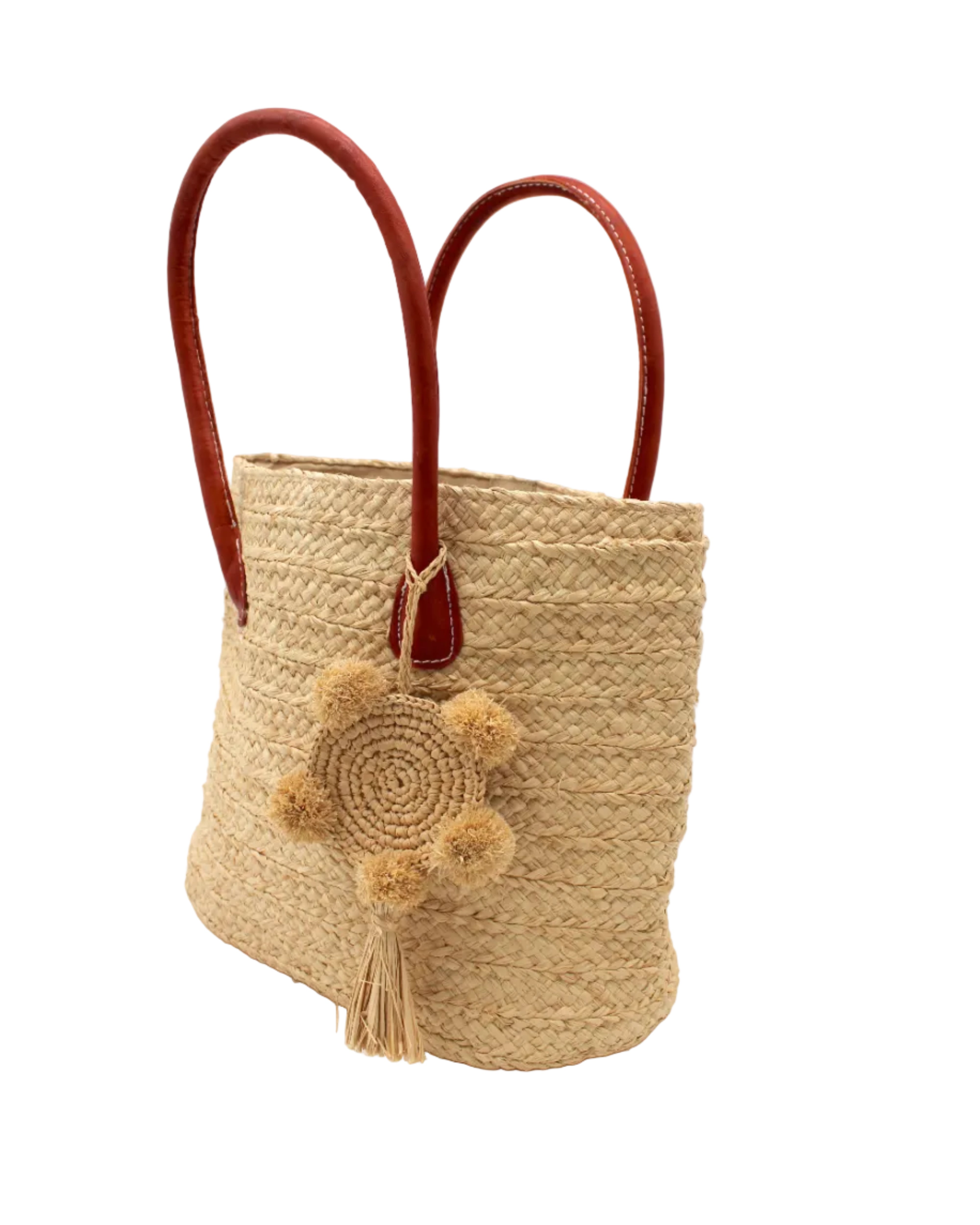 Side view Nomena Braided Straw Basket Handbag handmade braided natural raffia palm fiber in a solid hue of natural straw color woven into concentric horizontal bands of subtle texture spiraling around the bag with leather handles beach bag shoulder bag purse with matching crochet dreamcatcher pompom and tassel charm embellishment - Shebobo