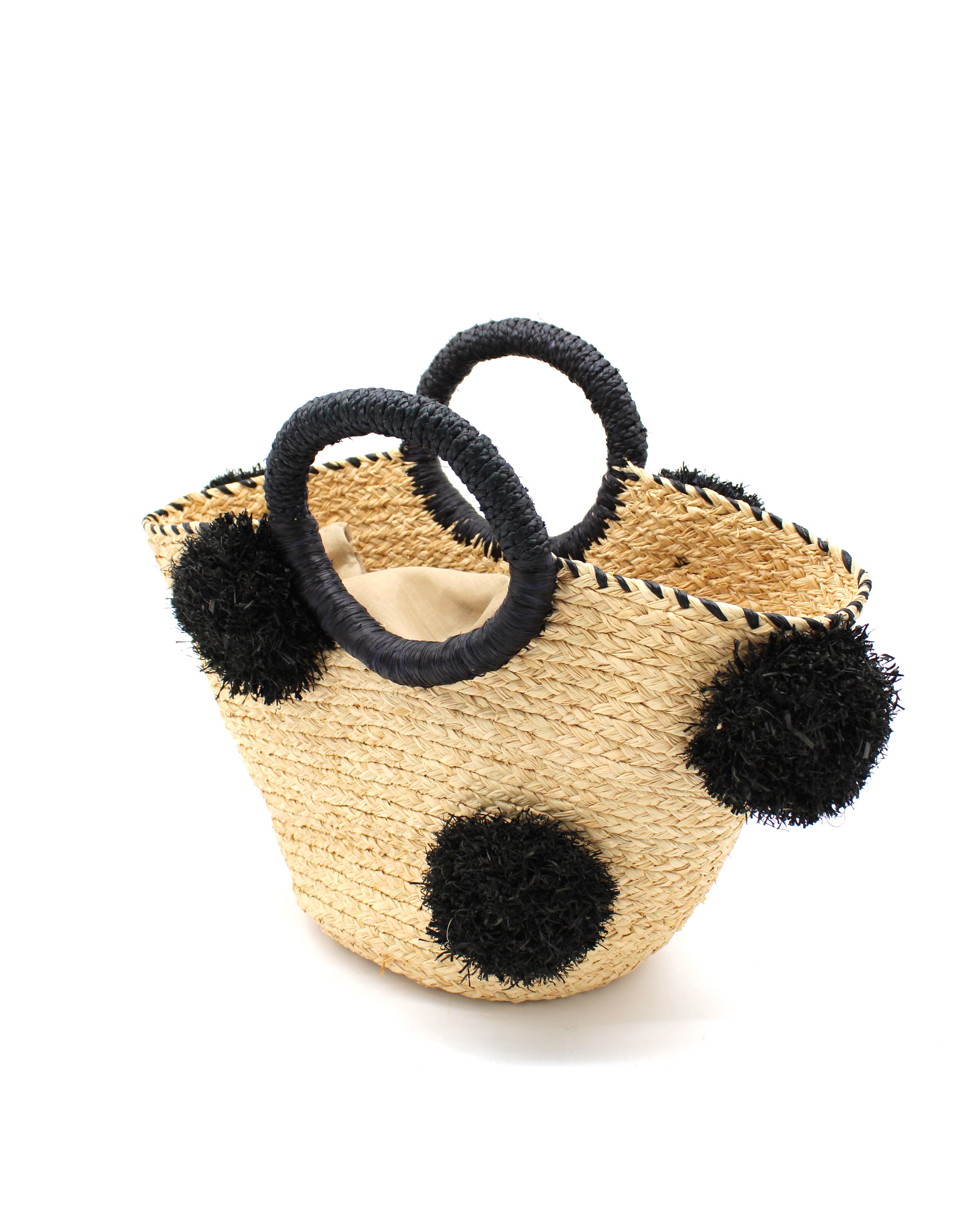 Side View Phi Phi Black and Natural Braided Straw Basket with Oversized Raffia Poufs handmade raffia palm fiber braided into a solid hue of natural straw color with three randomly placed black hand-brushed fringe poufs per side for embellishment with matching loop wrap top edging and matching crochet loop/braided handles bag handbag - Shebobo
