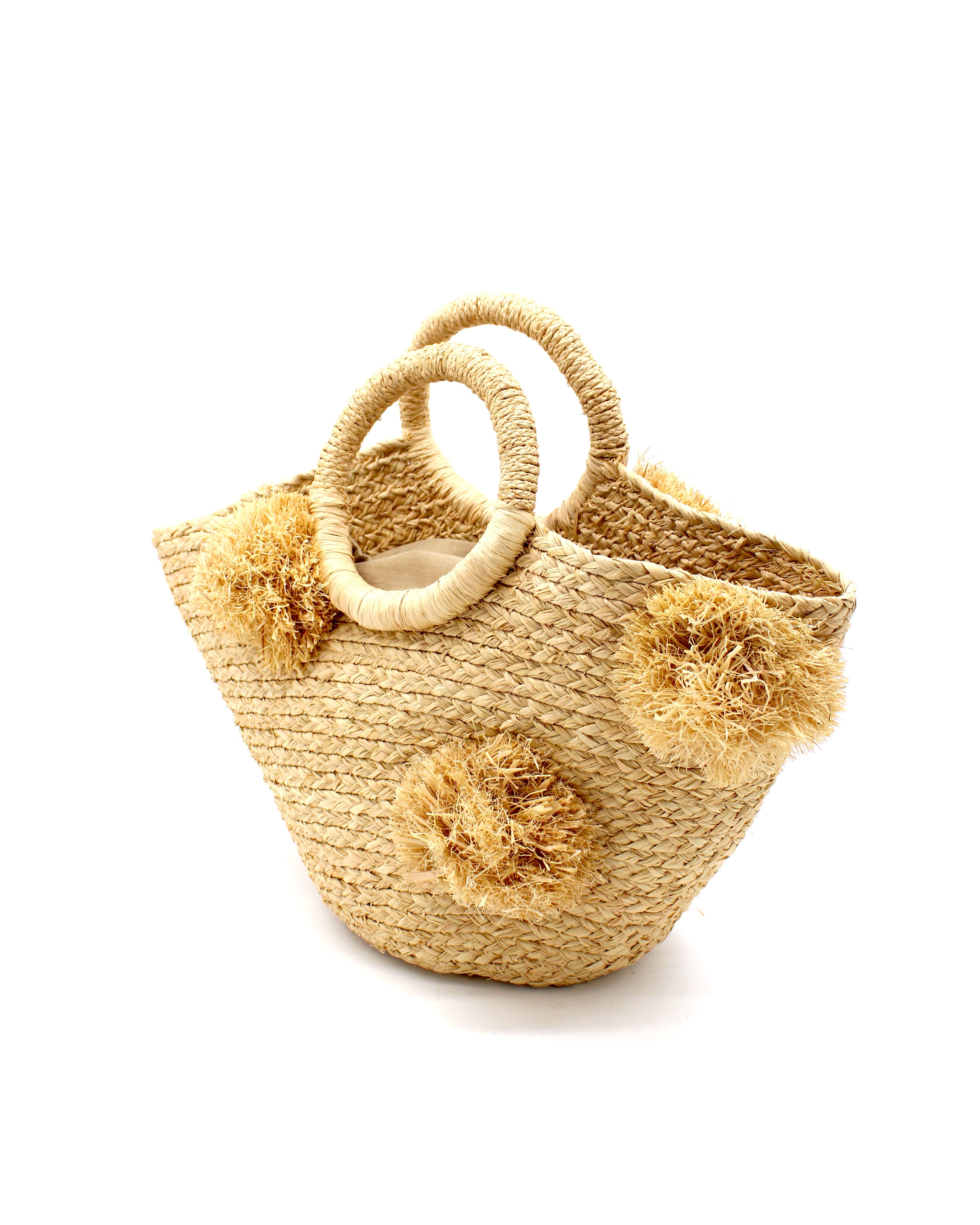 Side View Phi Phi  Natural Braided Straw Basket with Oversized Raffia Poufs handmade raffia palm fiber braided into a solid hue of natural straw color with three randomly placed matching hand-brushed fringe poufs per side for embellishment with loop wrap top edging and crochet loop/braided handles bag handbag - Shebobo