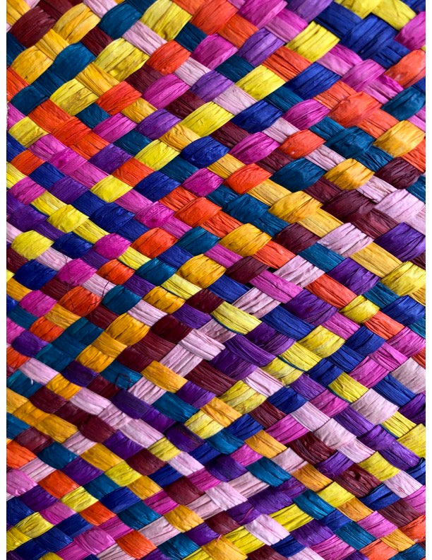 Detail view of Pianina Raspberry Multi Small Straw Basket Bag handmade from woven natural raffia palm fiber in a multicolor cross weave pattern of turquoise blue, coral orange, orchid purple, bordeaux red, fuchsia pink, light pink, saffron yellow, yellow, and navy blue handbag purse with leather handles - Shebobo