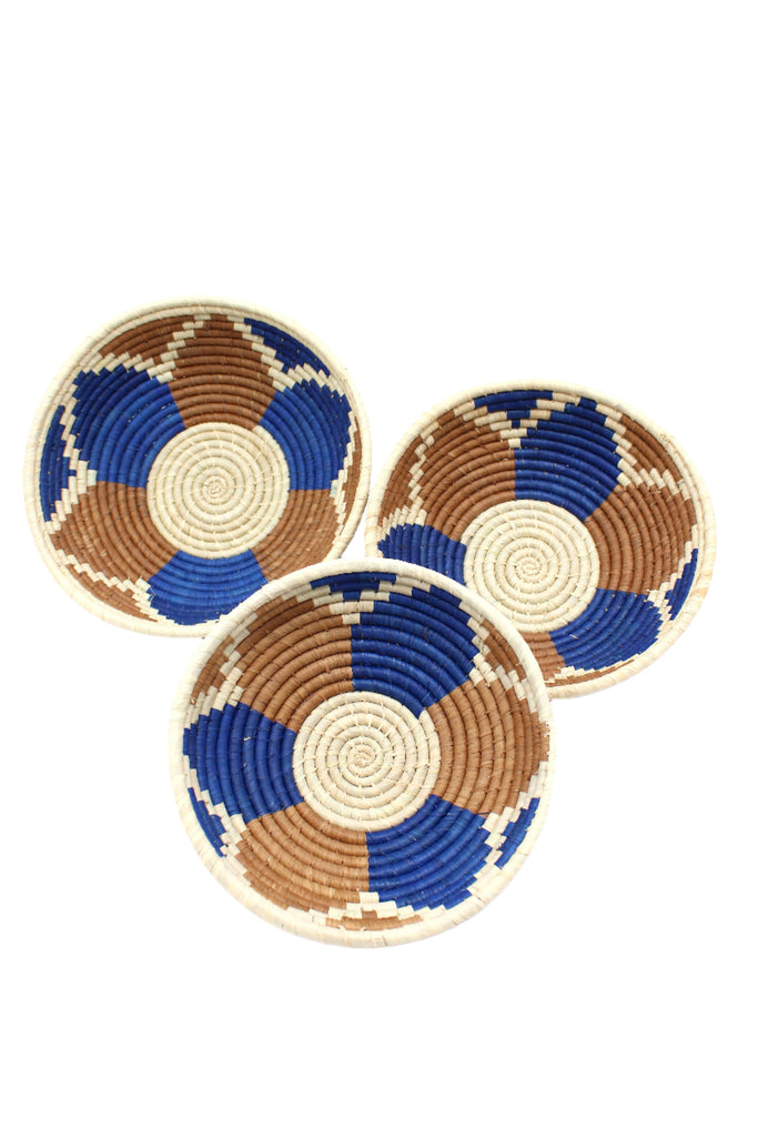 Raffia Straw Decor Display Basket Bowls: Set of 3 handmade woven natural raffia palm fiber in a crochet loop technique concentric coiled circular pattern with natural straw color centered in the bottom with blue, cinnamon/tobacco/brown, and natural geometric floral design pattern up the sides of the bowls set of small, medium, and large straw display bowls - Shebobo