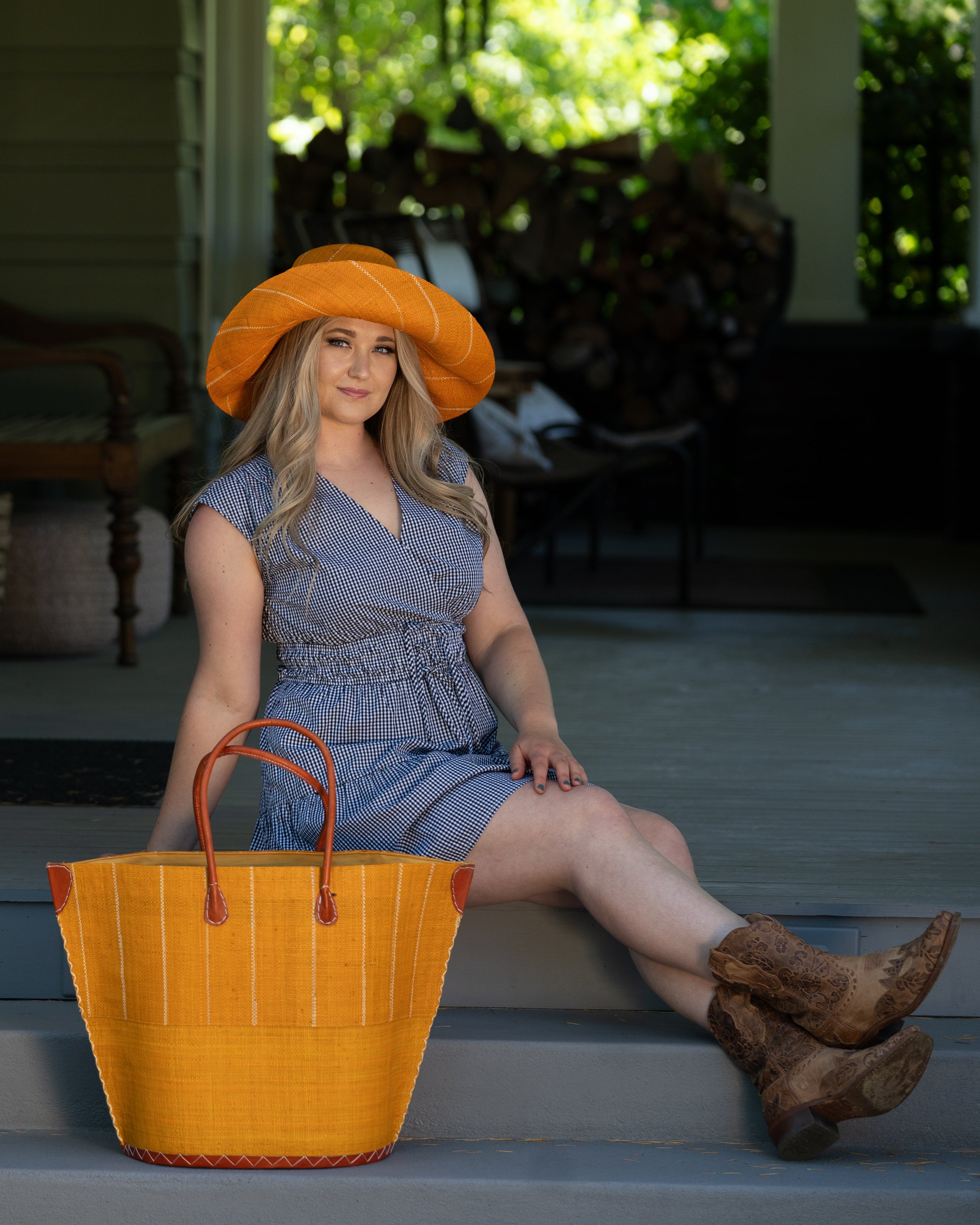 Model wearing Santa Cruz Two Tone Large Straw Tote Bag handmade beach bag loomed raffia solid saffron yellow/orange bottom with saffron and natural straw color vertical pinstripe pattern top half plus leather handles xl handbag shoulder bag - Shebobo (with Monica 5" & 7" Wide Brim Multicolor Pinstripe Pattern Packable Straw Sun Hats)