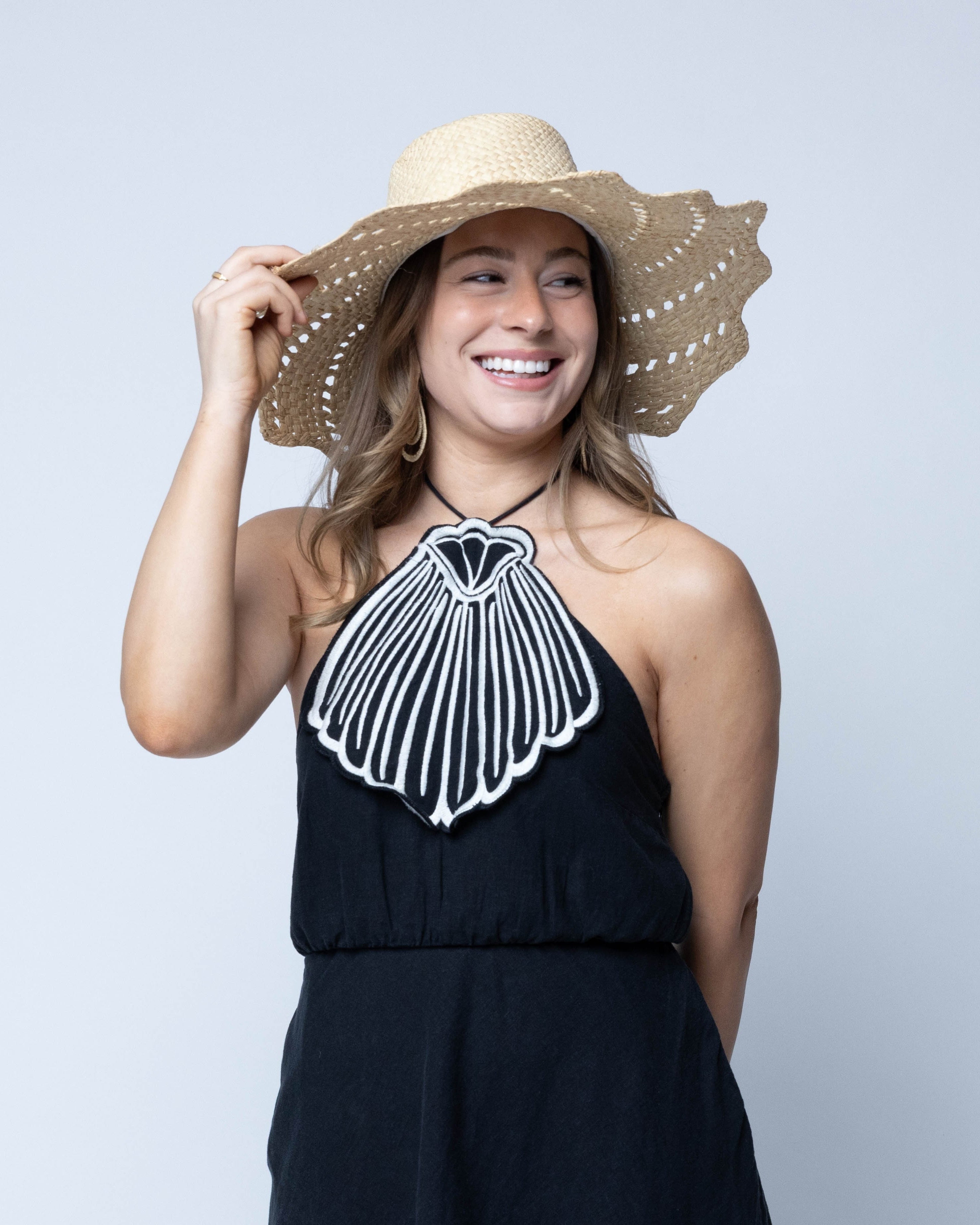Model wearing Sara 4.5" Brim Woven Straw Sun Hats with Zigzag Edge handmade natural raffia palm fiber in a solid hue of Natural straw color woven with a subtle crosshatch texture across the crown and spiraling open weave across the brim with matching hat band and zigzag edge - Shebobo