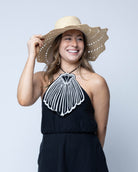 Model wearing Sara 4.5" Brim Woven Straw Sun Hats with Zigzag Edge handmade natural raffia palm fiber in a solid hue of Natural straw color woven with a subtle crosshatch texture across the crown and spiraling open weave across the brim with matching hat band and zigzag edge - Shebobo