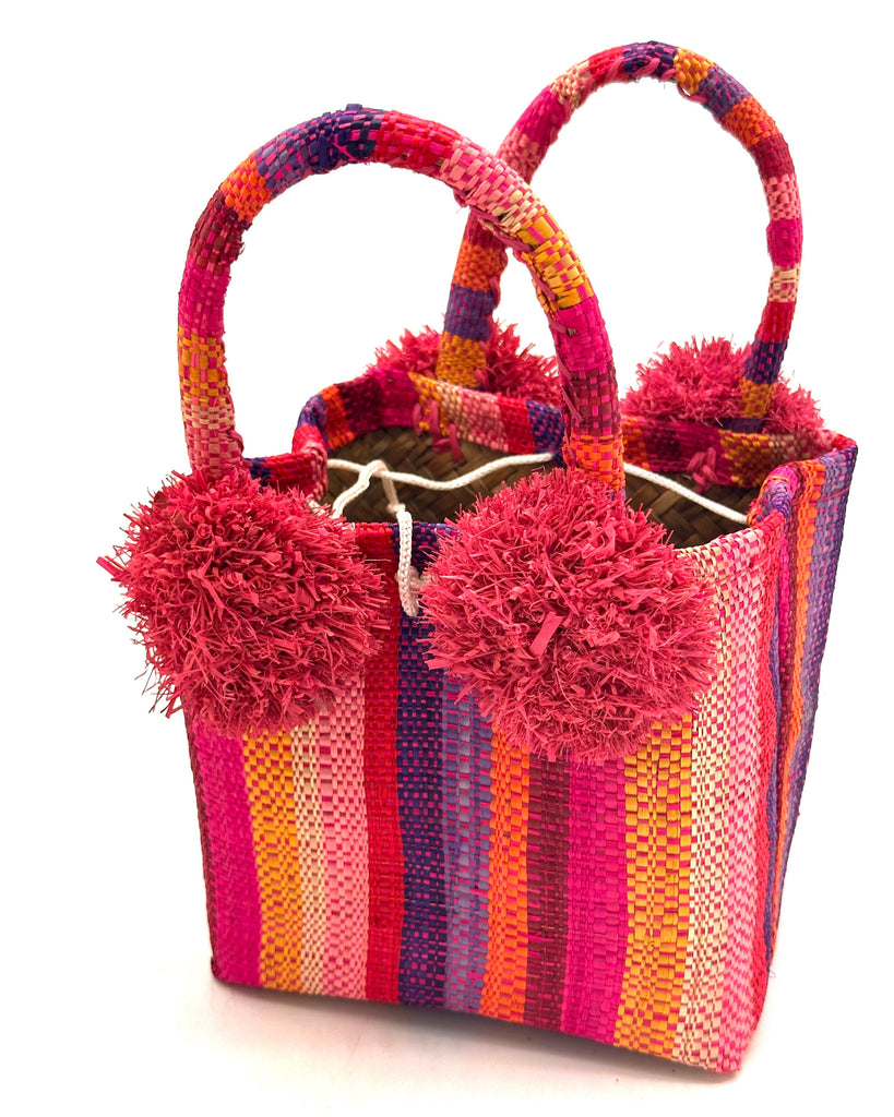 Schooner Fiesta Swirl Straw Mini Bag with Pompom Accent handmade loomed natural raffia palm fiber in multi width vertical multicolor stripe pattern of purple, orange, pink, red, blue, natural straw color, yellow, etc. with four matching raffia pompom embellishments at the base of each handle attachment tiny purse extra small handbag - Shebobo
