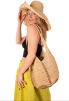 Model wearing Sea See Cappuccino Straw Shoulder Bag handmade woven raffia palm fiber in a solid hue of natural straw color making a diagonal link pattern with cappuccino light/brown/beige crochet circular bottom and vertical edging along the side panels creating a two tone multicolor handbag/beach bag/purse - Shebobo (with 5" & 7" Wide Brim Packable Straw Sun Hat)