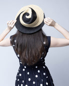 Model wearing Sequoia Black and Natural 3" Brim Swirl Crochet Panama Unisex Straw Hats handmade crochet natural raffia palm fiber in a two tone color swirl design of black and natural straw color spiraling together from wide bands around the brim to a narrow twist at the top of the crown  - Shebobo