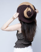 Model wearing Sequoia Cappuccino & Espresso 3" Brim Swirl Crochet Panama Unisex Straw Hats handmade crochet natural raffia palm fiber in a two tone color swirl design of cappuccino tea/light/brown and espresso dark/chocolate/brown spiraling together from wide bands around the brim to a narrow twist at the top of the crown  - Shebobo