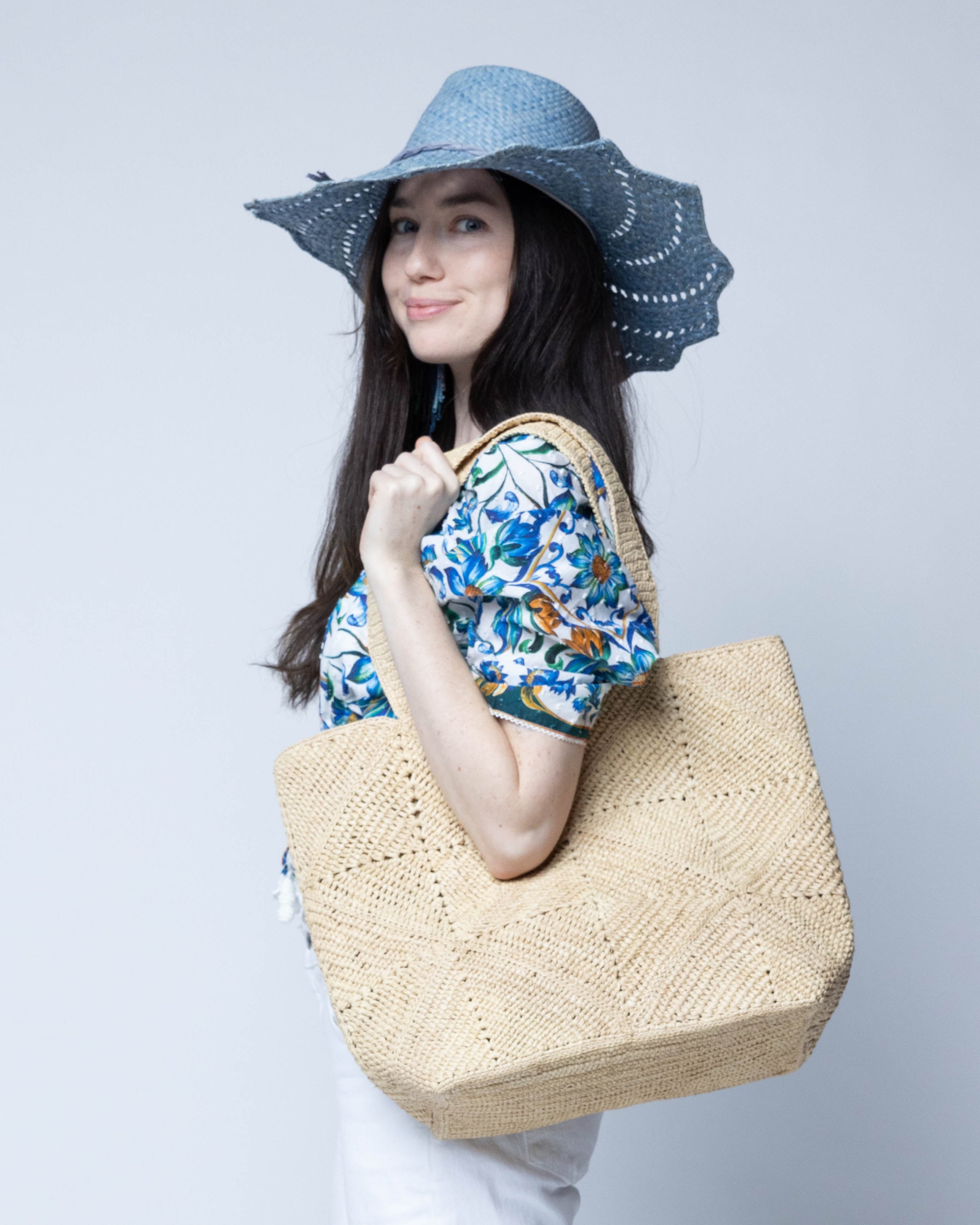 Model wearing Seychelle Natural Diamond Pattern Crochet Straw Basket Handbag handmade natural raffia palm fiber in a solid hue of natural straw color with subtle geometric diamond diagonal pattern with matching crochet handles beach bag tote purse - Shebobo (with Sara 4.5" Brim Woven Straw Sun Hats with Zigzag Edge)