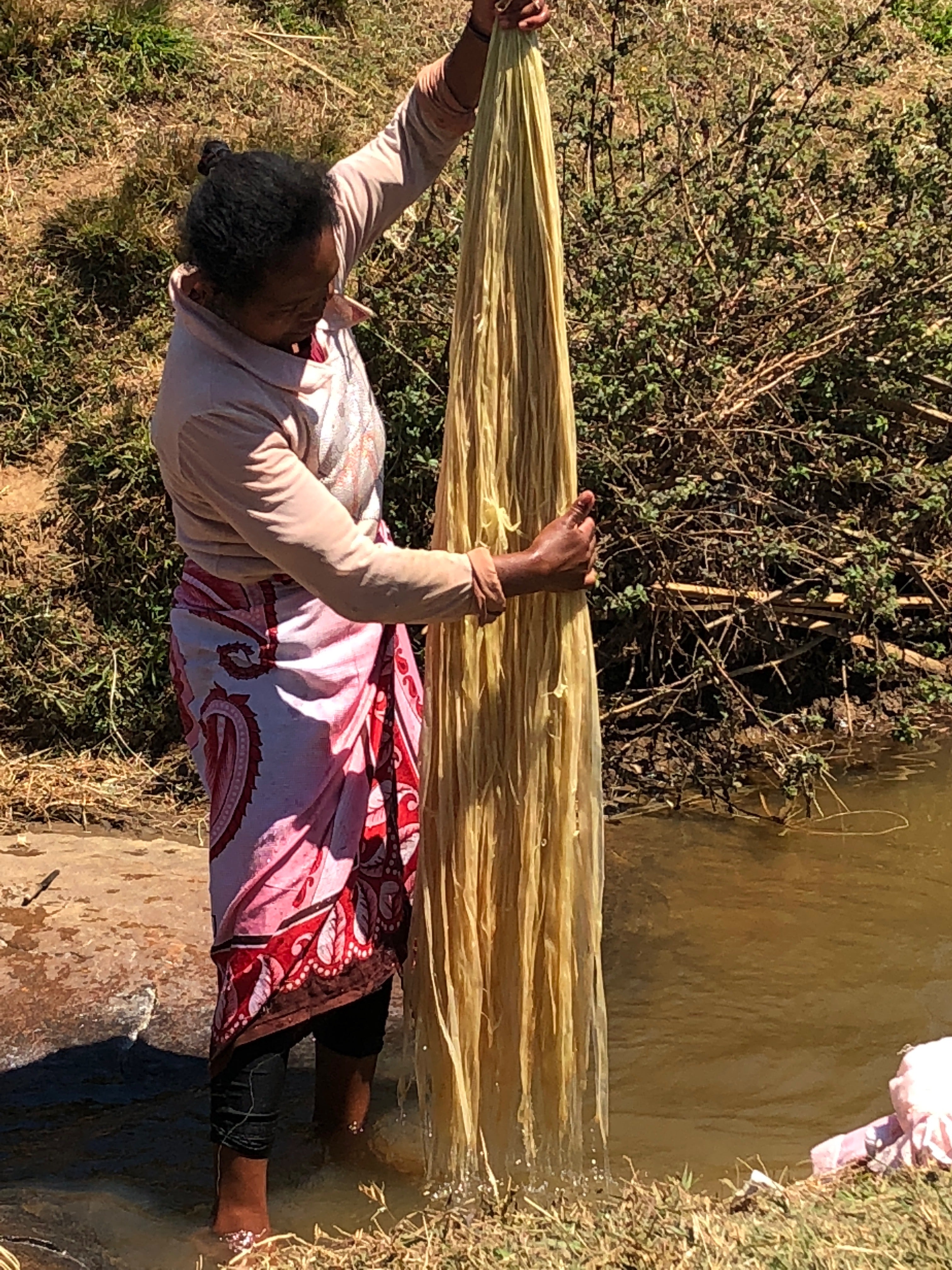 Shebobo Artisan in Madagascar washing raffia palm fibers to be used in handmade loomed or crochet natural resources straw accessories for Shebobo