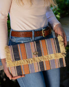 Model wearing Sophie Retro Stripe Multicolor Stripes Straw Clutch handmade loomed raffia purse handbag  in muti-width vertical bands of denim retro/light/blue, dusk navy/dark/blue, light pink, coral orange/red and natural straw color with matching cross stitch edging and natural straw color raw fringe edge envelope shaped bag - Shebobo