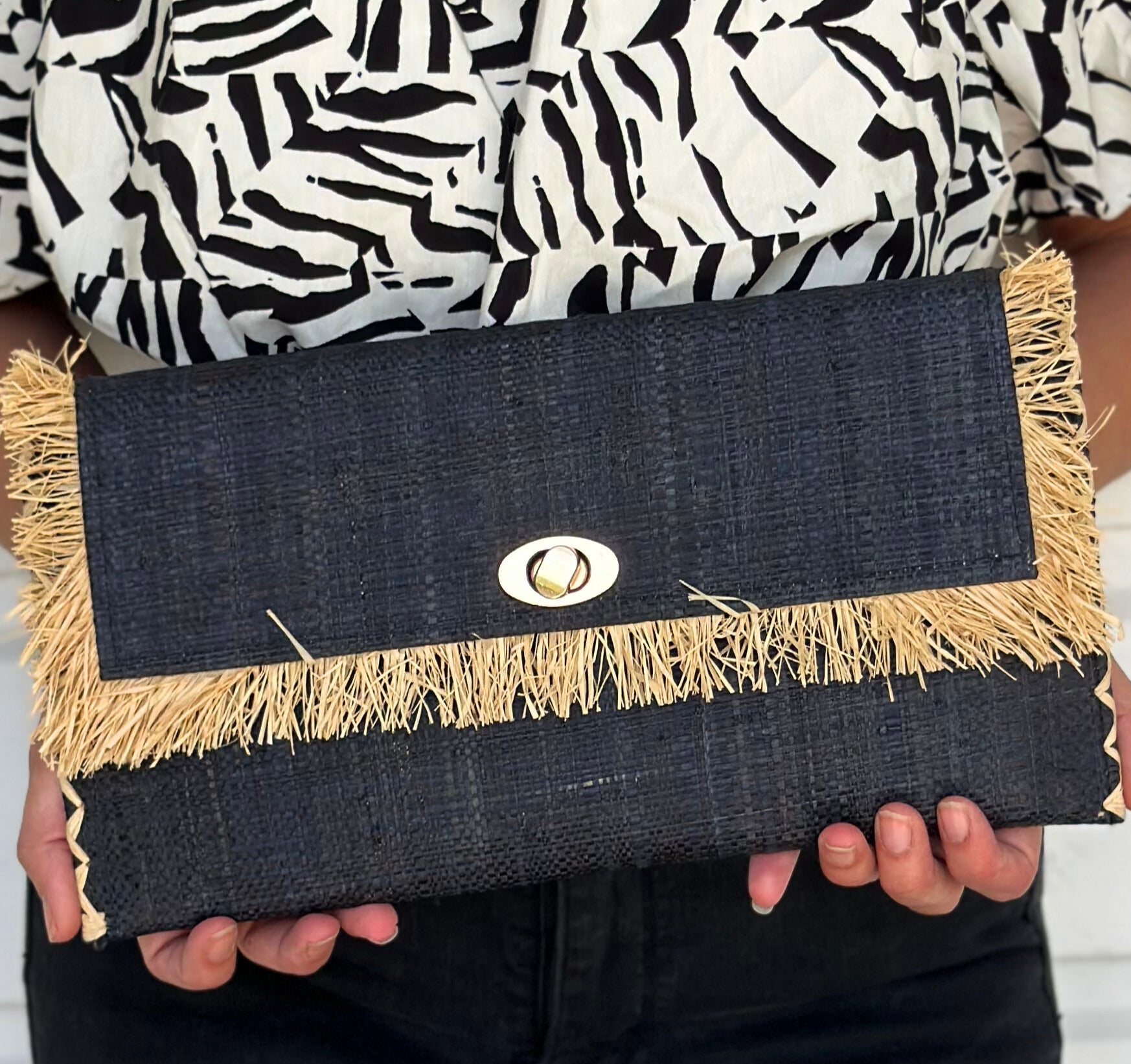 Model wearing Sophie Black Straw Clutch with Raw Fringe Edge handmade loomed black raffia purse with contrasting natural straw color fringe trim edge and matching cross stitch binding handbag - Shebobo