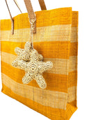 Side view Starfish Straw Bag with Crochet Starfish Charm Embellishment handmade loomed raffia shopping tote in saffron yellow and natural straw color horizontal wide stripe pattern handbag with leather handles - Shebobo