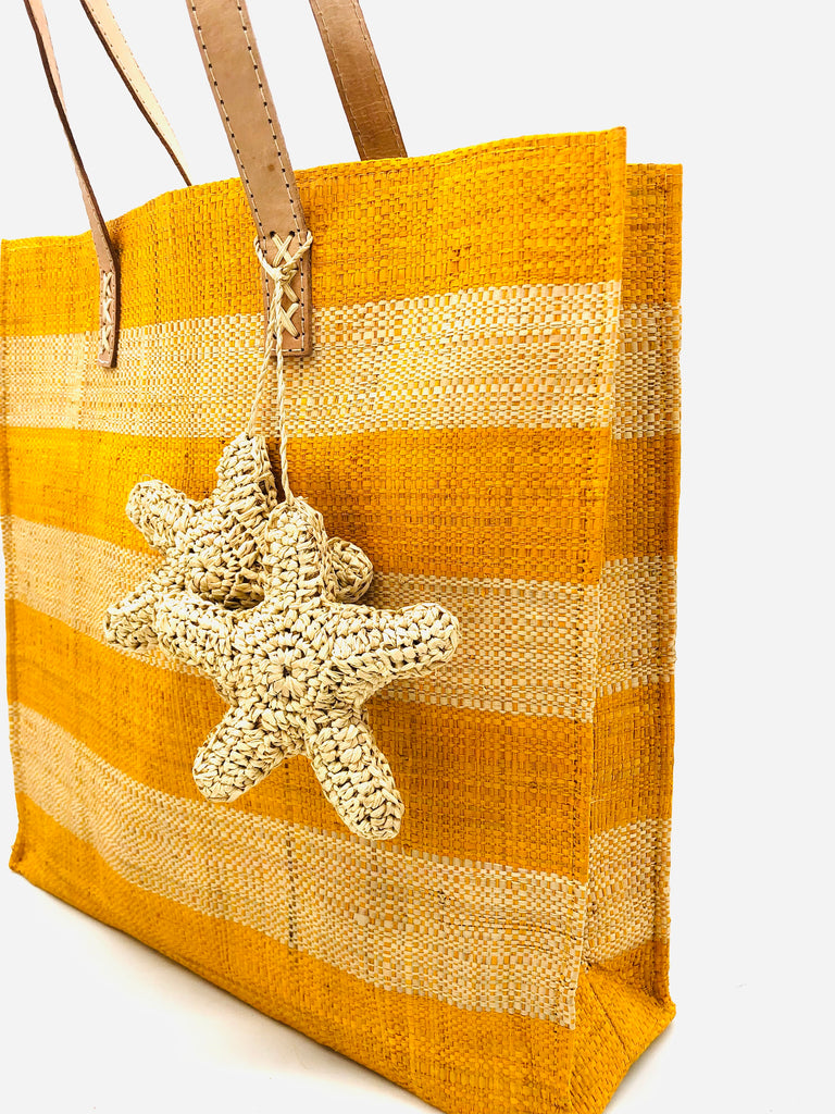 Side view Starfish Straw Bag with Crochet Starfish Charm Embellishment handmade loomed raffia shopping tote in saffron yellow and natural straw color horizontal wide stripe pattern handbag with leather handles - Shebobo