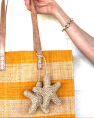 Model wearing Starfish Tie Crochet Raffia Charm Embellishment handmade natural raffia palm fiber is crochet into 3D starfish shapes in natural straw color and connected with raffia twist tie beach bag embellishment - Shebobo