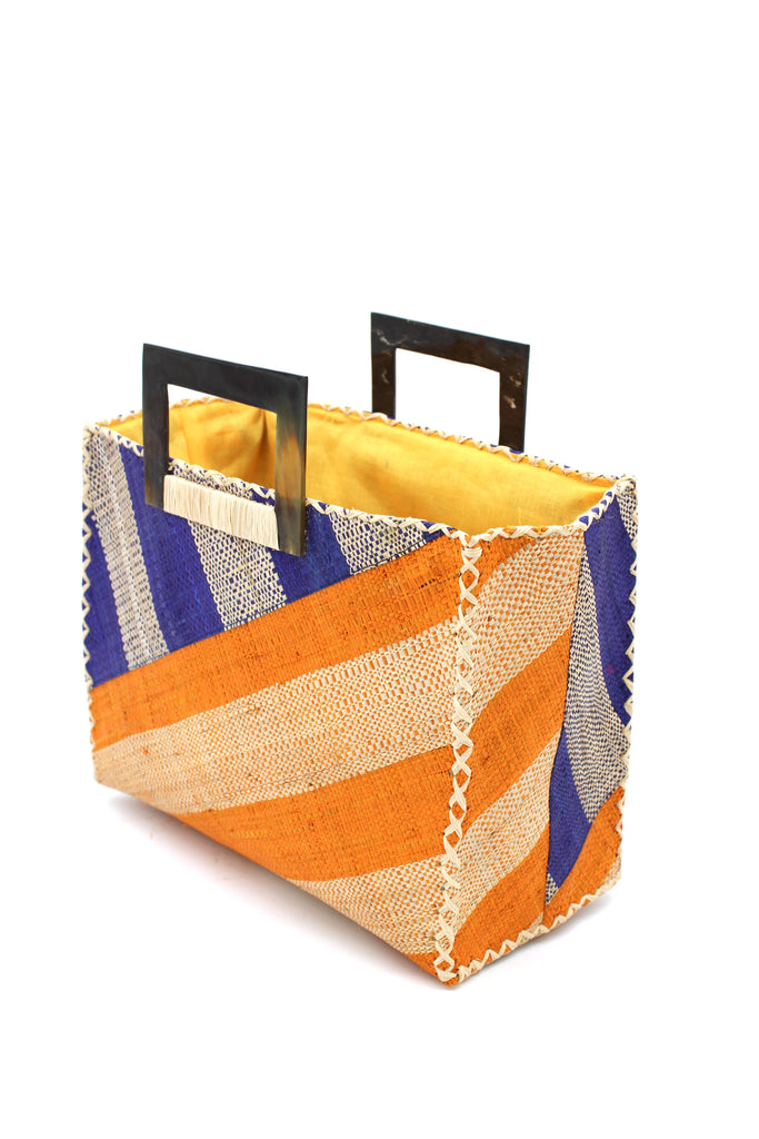 Side View Stevie Double Wide Stripe Saffron & Dusk Square Straw Handbag with Horn Handles handmade loomed raffia palm fiber in even width wide stripe pattern of Saffron yellow/orange and natural straw color oriented on the diagonal of three quarters of the bag with matching stripe pattern of Dusk navy/dark/blue and natural diagonally on the top left corner quarter shoulder bag handbag - Shebobo