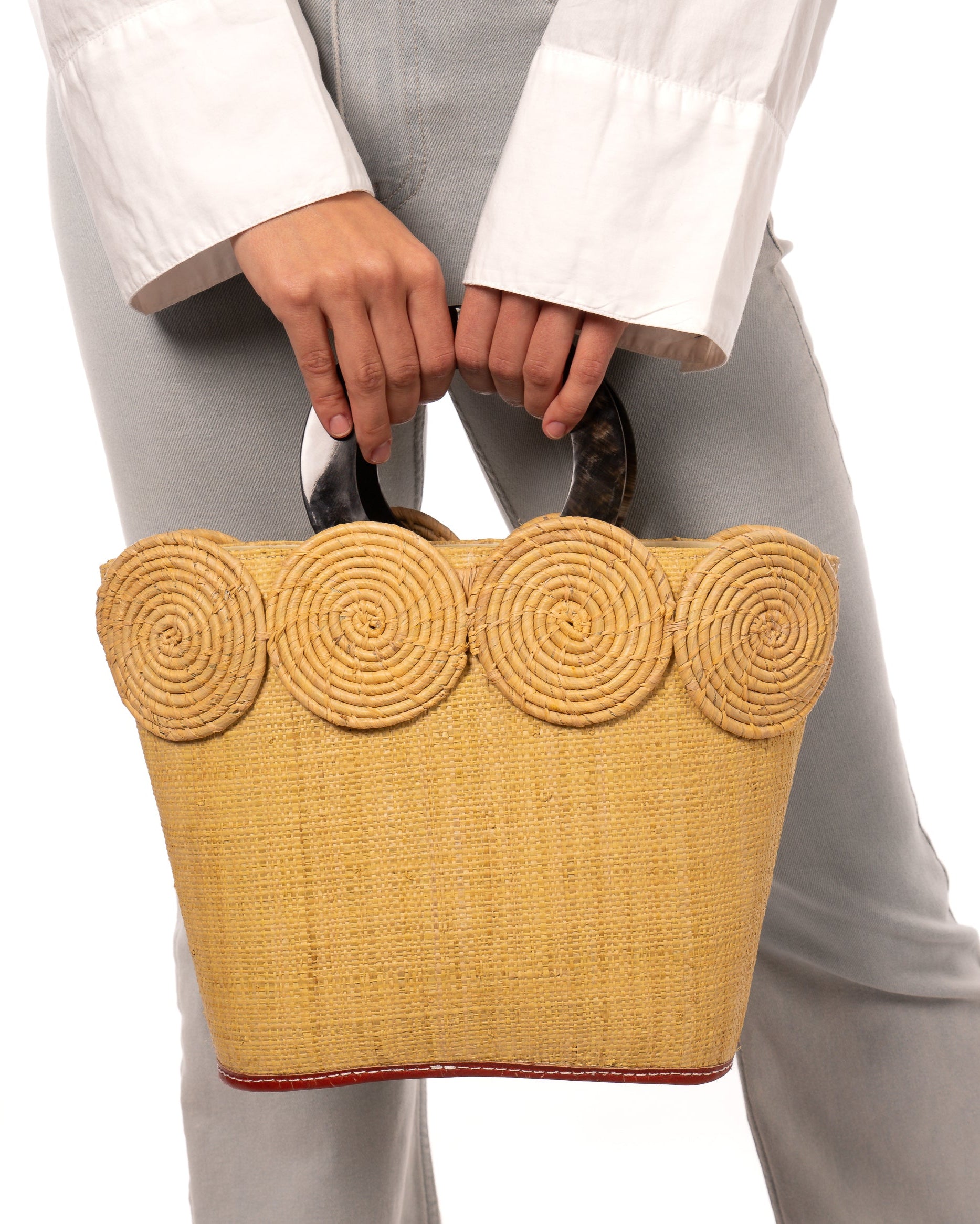 Model wearing Tazi Disc Straw Handbag with Horn Handle handmade loomed raffia purse in butter light/yellow with matching wrapped raffia disc embellishment small bag - Shebobo