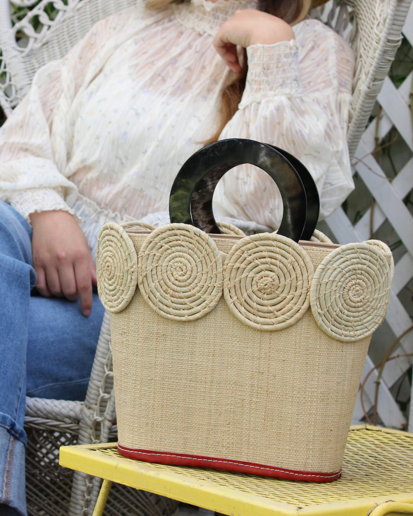 Model wearing Tazi Disc Straw Handbag with Horn Handle handmade loomed raffia purse in natural straw color with matching wrapped raffia disc embellishment small bag - Shebobo