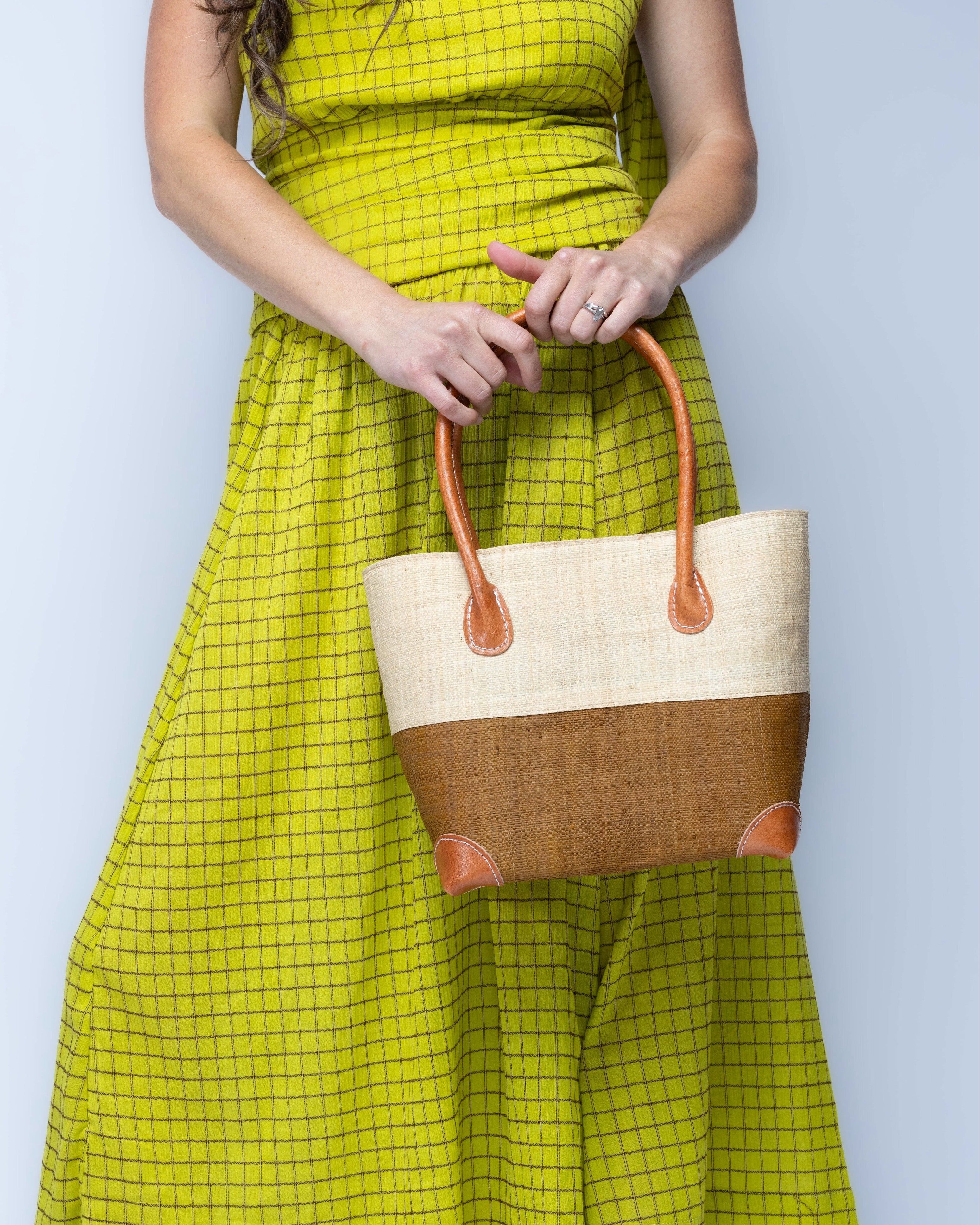Model wearing Small Trinidad Natural and Tobacco Two Tone Straw Basket Bag handmade loomed raffia palm fiber in a two tone color block pattern with tobacco cinnamon/dark/brown on the bottom half and natural straw color on the top half of the bag with leather handles and accents beach bag tote purse - Shebobo