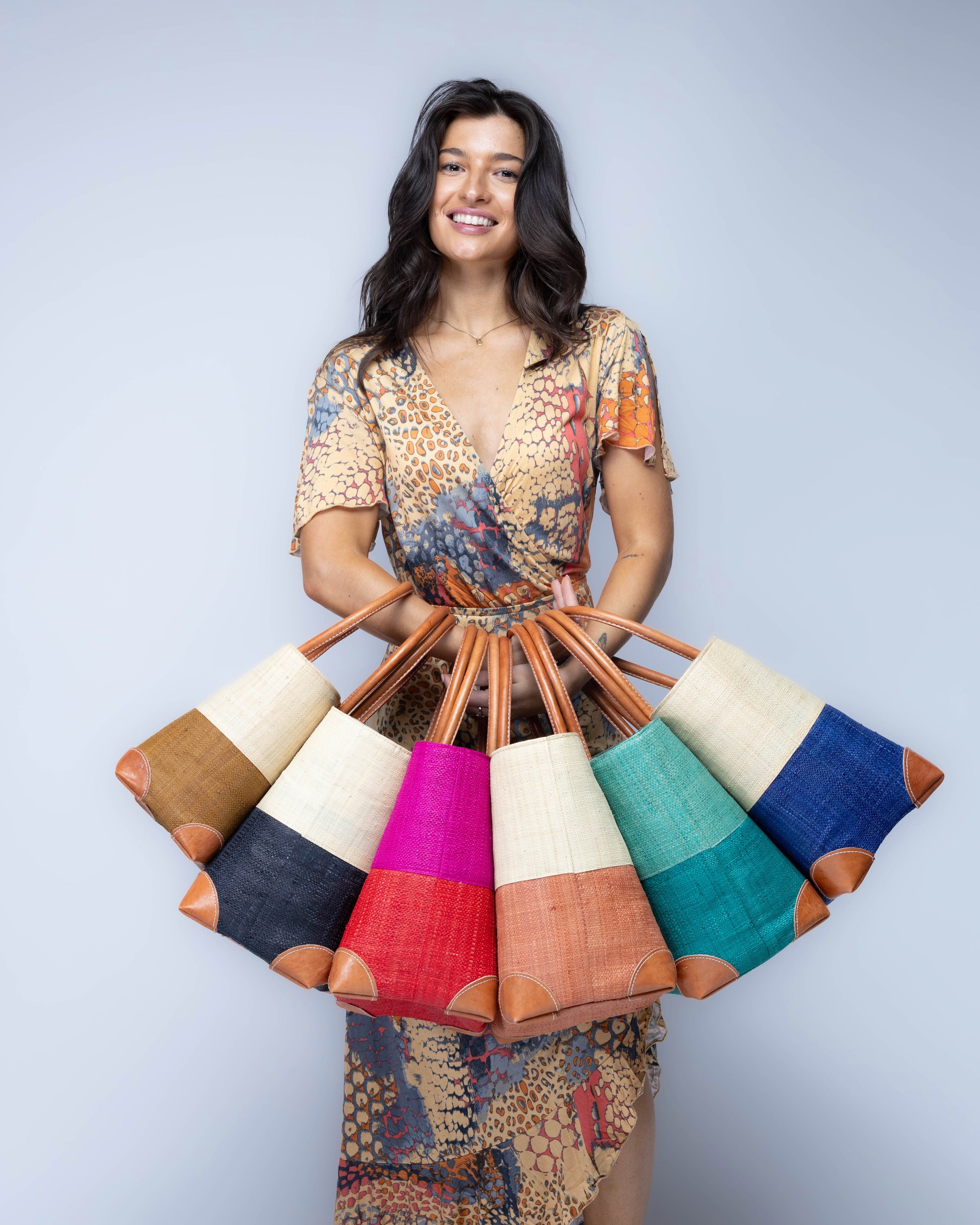 Model wearing multiple color options of Trinidad Two Tone Straw Basket Bags handmade loomed raffia palm fiber in a two tone color block patterns with leather handles and accents beach bag tote purse - Shebobo