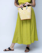 Model wearing Tulum Straw Bucket Bag with Flower Embroidery and Horn Handle Butter Purse with Ruffle Edge handmade loomed raffia palm fiber in a solid hue of butter light/yellow with natural straw color hand embroidered floral pattern with multiple sized flowers and raffia ruffle on the opening  handbag - Shebobo