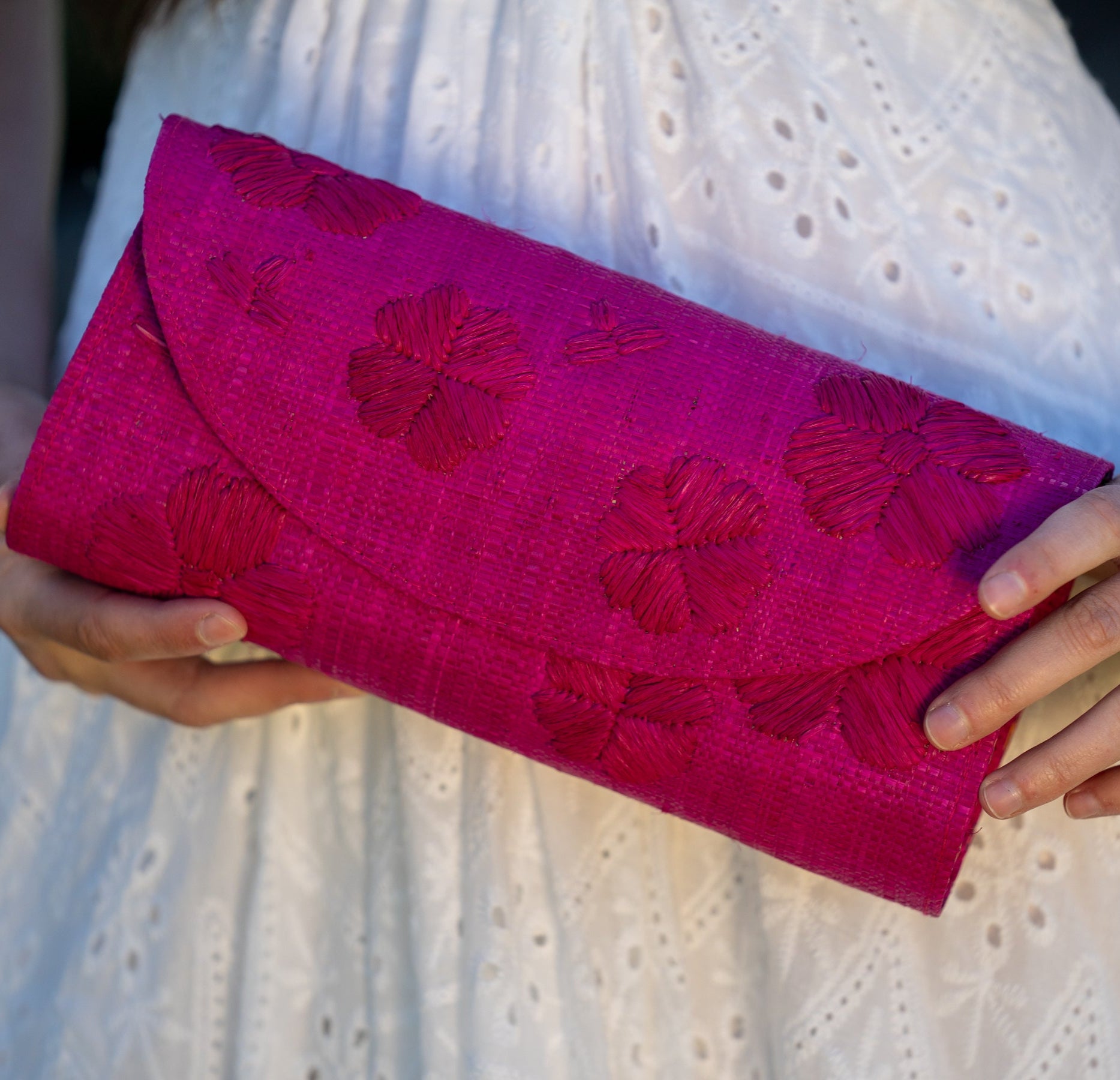 Model wearing Tulum Clutch Fuchsia hot/bright/barbie/pink Flower Embroidery handmade loomed raffia palm fibers with envelope clutch shape, embroidered multi-sized embroidered flower pattern, and assorted interior wax cloth African Print liners plus zippered pocket  - Shebobo