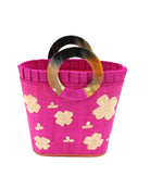 Tulum Straw Bucket Bag with Flower Embroidery and Horn Handle Fuchsia Purse with Ruffle Edge handmade loomed raffia palm fiber in a solid hue of fuchsia hot/bright/barbie/pink with natural straw color hand embroidered floral pattern with multiple sized flowers and raffia ruffle on the opening  handbag - Shebobo