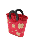 Side view Tulum Straw Bucket Bag with Flower Embroidery and Horn Handle Red Purse with Ruffle Edge handmade loomed raffia palm fiber in a solid hue of red with natural straw color hand embroidered floral pattern with multiple sized flowers and raffia ruffle on the opening  handbag - Shebobo