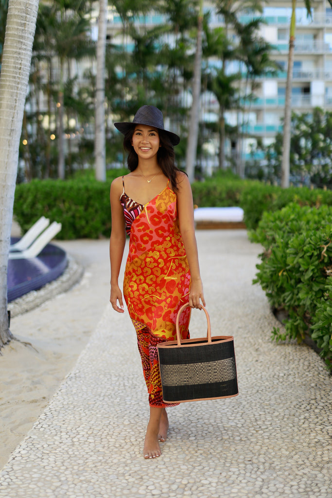 Model wearing Wynwood Black Straw Basket Bag Handbag with Metallic Detailing handmade loomed raffia in black and silver metallic vegan leather in three evenly sized horizontal bands of color with the metallic weave centered on the purse with leather binding and handles - Shebobo (with Panama Black Unisex Straw Hat)