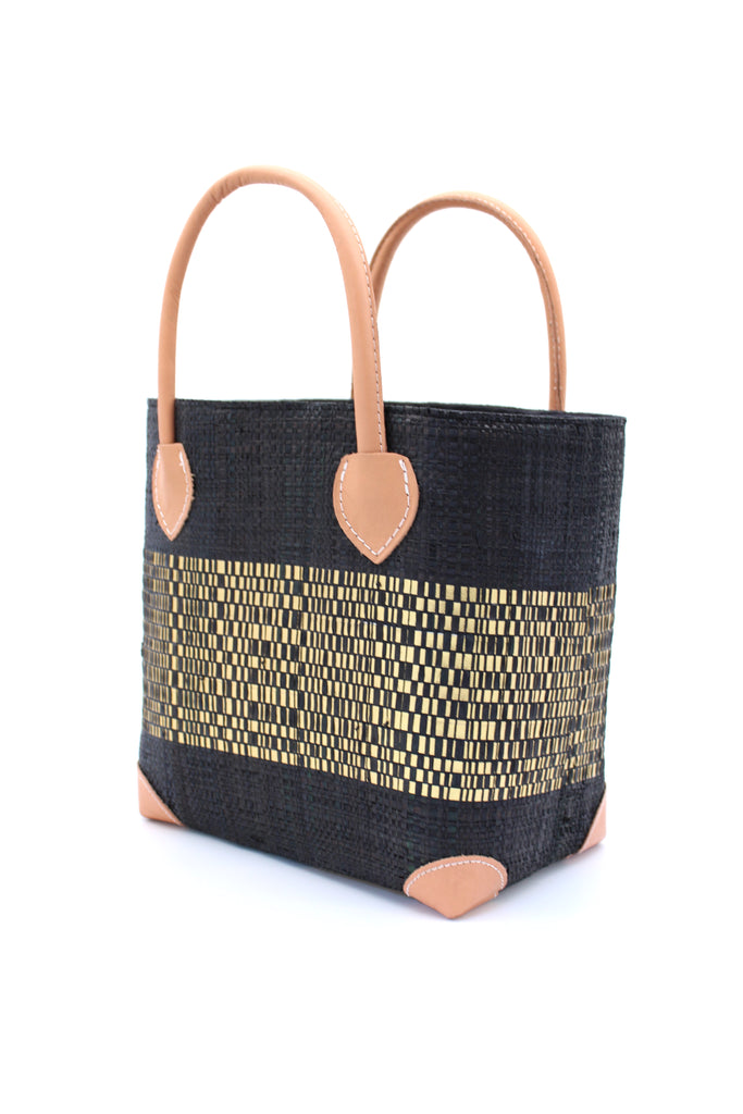 Side View Wynwood Black Straw Basket Bag with Metallic Detailing Handmade loomed raffia palm fiber in a solid hue of black with a wide horizontal band of metallic strands woven in seamlessly handbag purse with leather handles - Shebobo