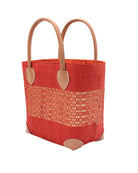 Side View Wynwood Coral Straw Basket Bag with Metallic Detailing Handmade loomed raffia palm fiber in a solid hue of coral orange/red with a wide horizontal band of metallic strands woven in seamlessly handbag purse with leather handles - Shebobo