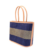 Side View Wynwood Blue Straw Basket Bag Handbag with Metallic Detailing handmade loomed raffia in blue and silver metallic vegan leather in three evenly sized horizontal bands of color with the metallic weave centered on the purse with leather binding and handles - Shebobo