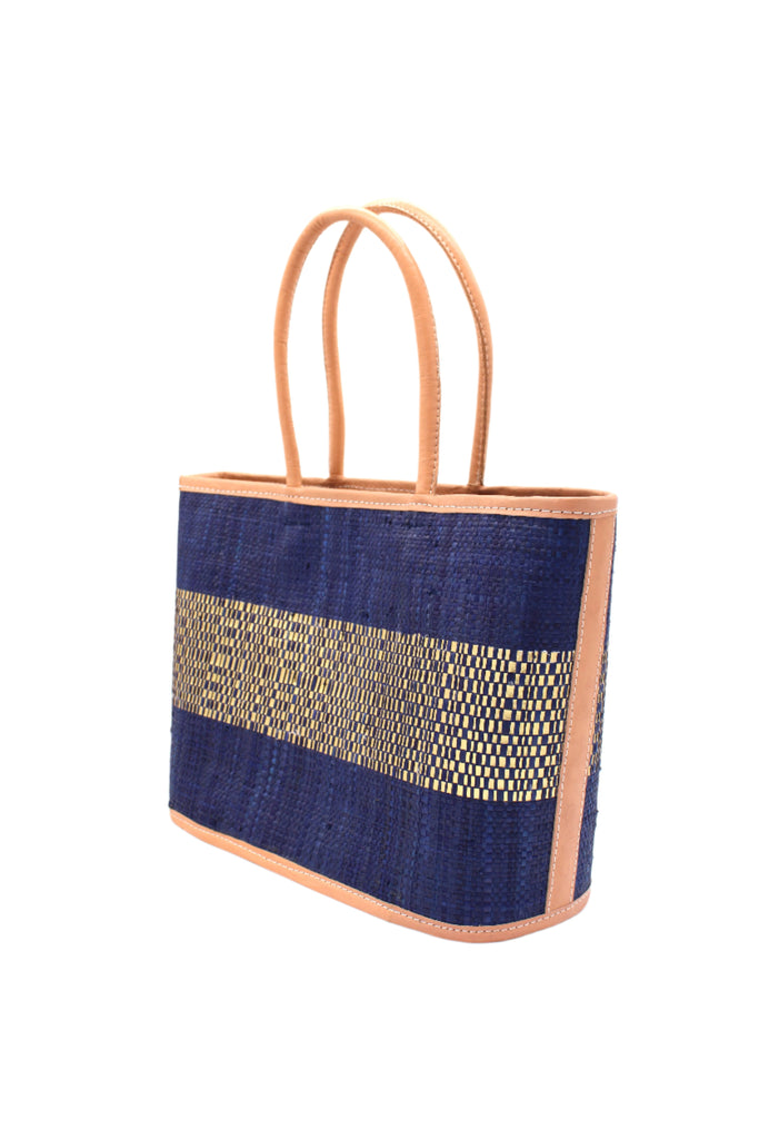 Side View Wynwood Blue Straw Basket Bag Handbag with Metallic Detailing handmade loomed raffia in blue and silver metallic vegan leather in three evenly sized horizontal bands of color with the metallic weave centered on the purse with leather binding and handles - Shebobo